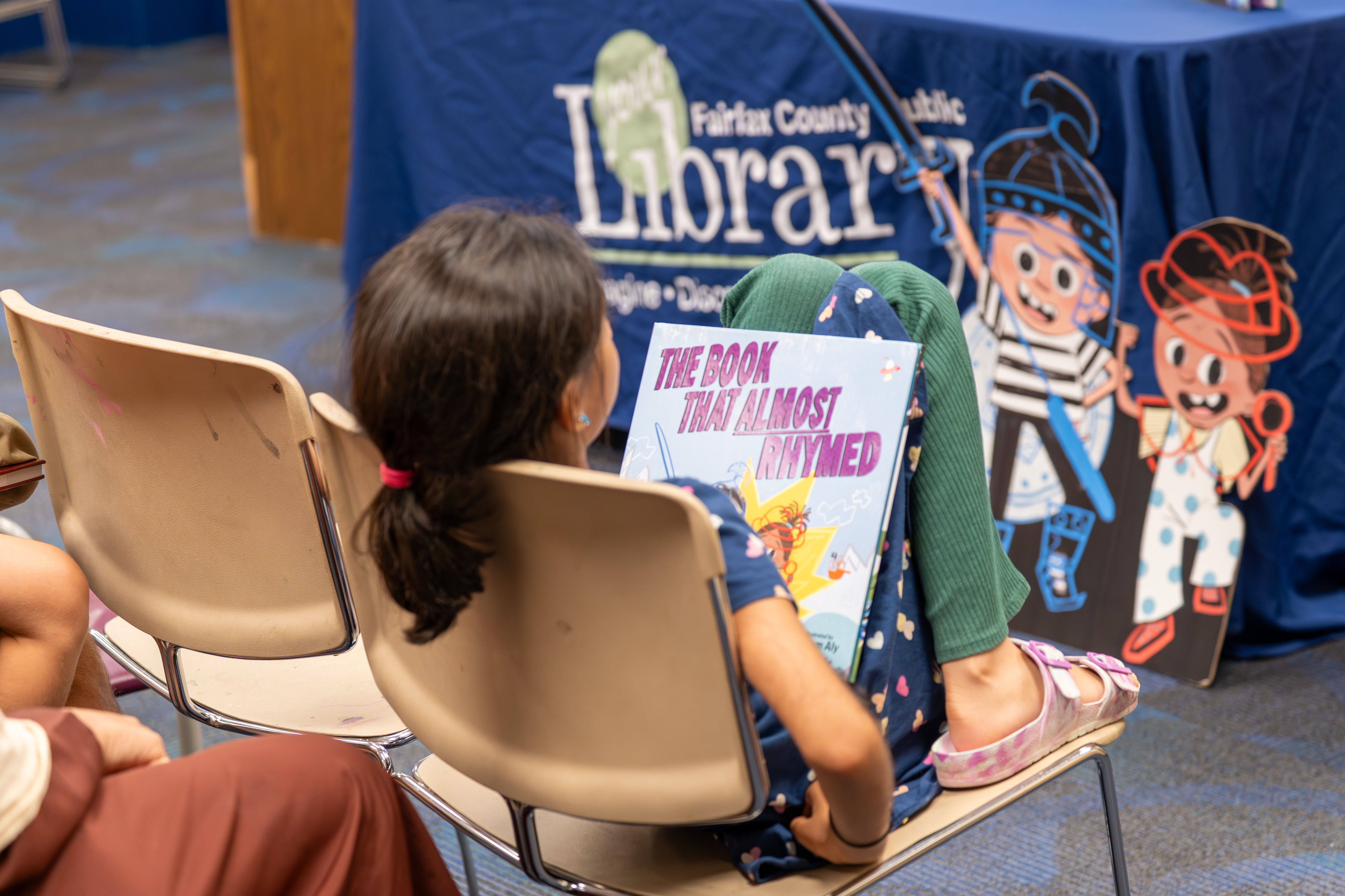 A child listens with The Book That Almost Rhymed in their lap
