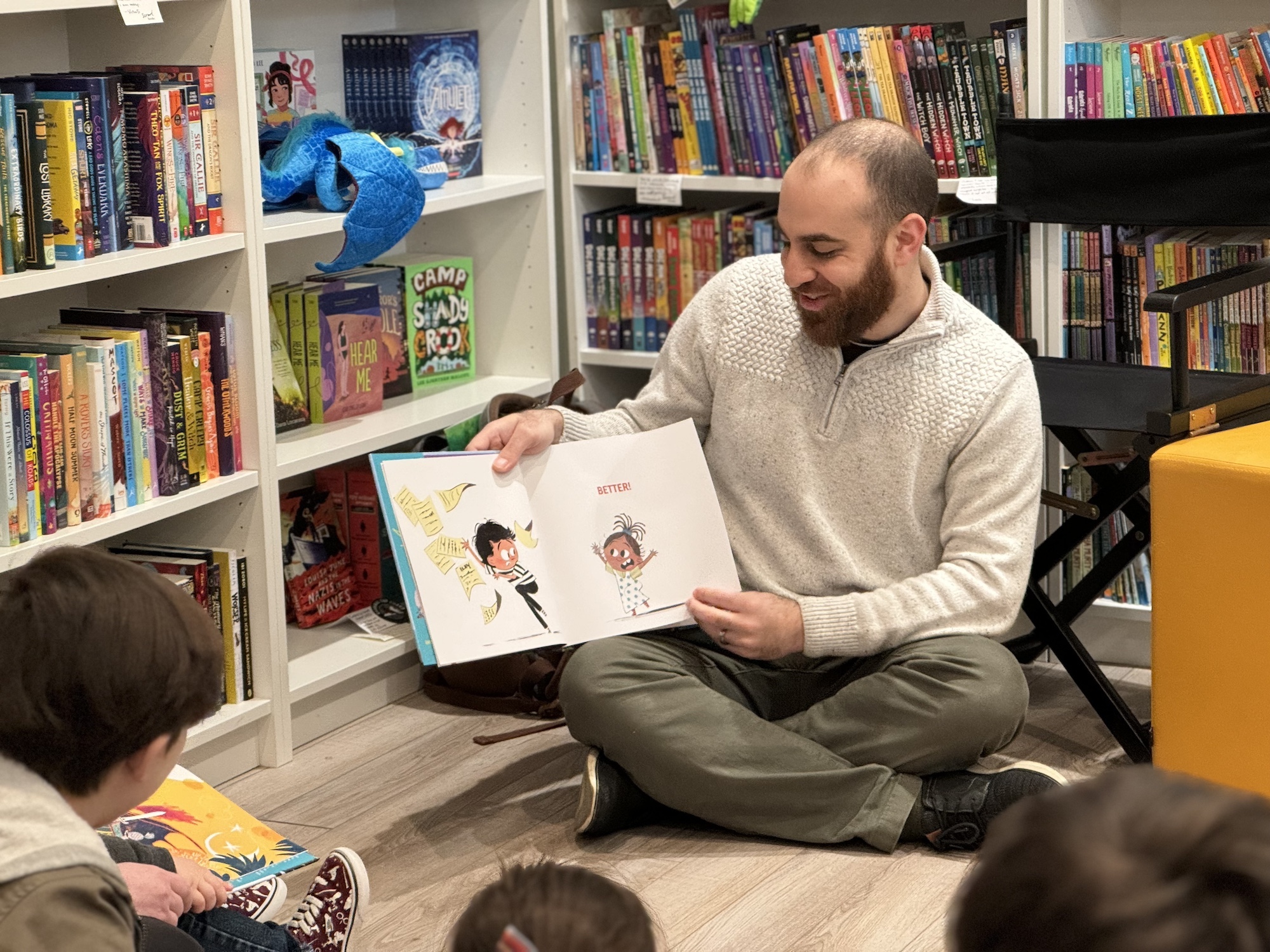 Omar sitting on the floor, reading The Book That Almost Rhymed at Scrawl Books