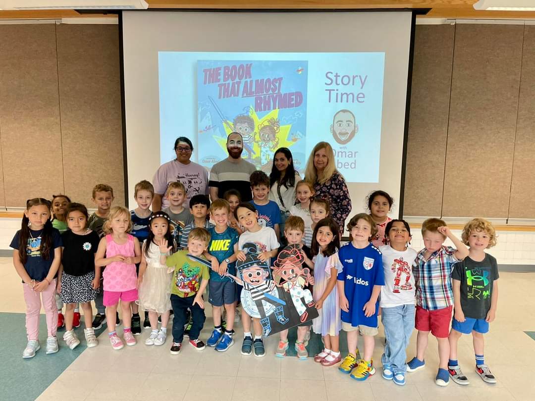 A class poses with Omar and teachers