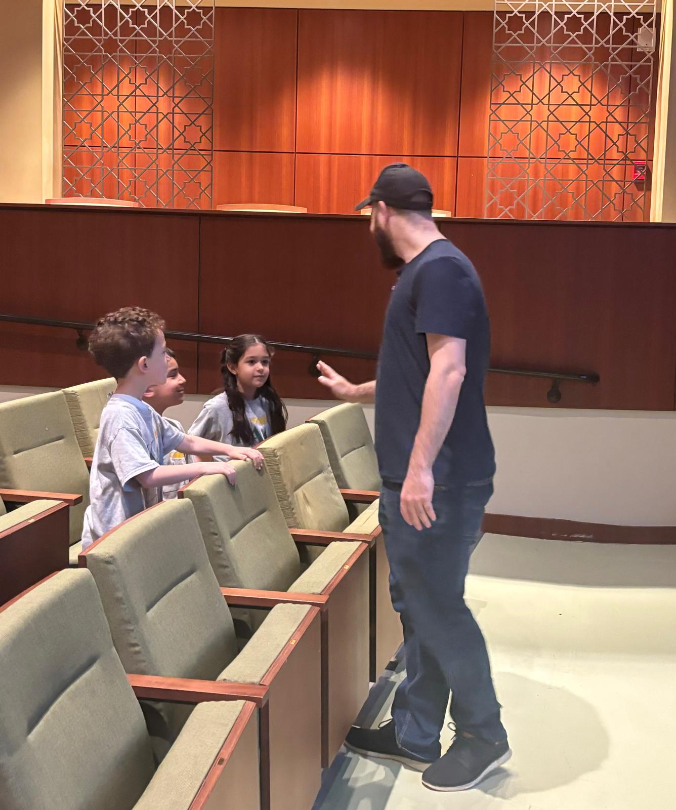 Omar greeting students in the auditorium